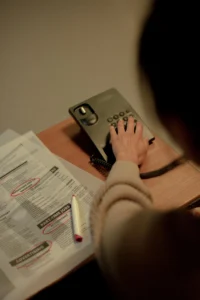 Pohľad zozadu na človeka pri stole, ktorý telefonuje a prezerá si noviny s označenými inzerátmi na pracovné miesta.