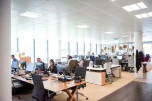 Pohľad na veľkú modernú open-space kanceláriu s ľuďmi pracujúcimi za počítačmi